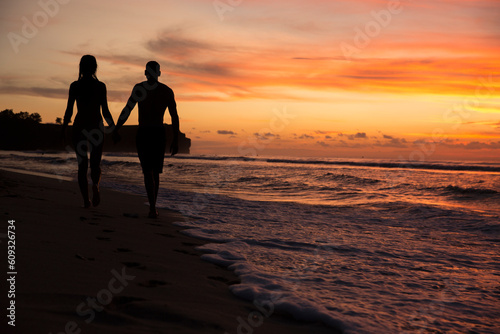 silhouette of couple walking on the beach at sunset