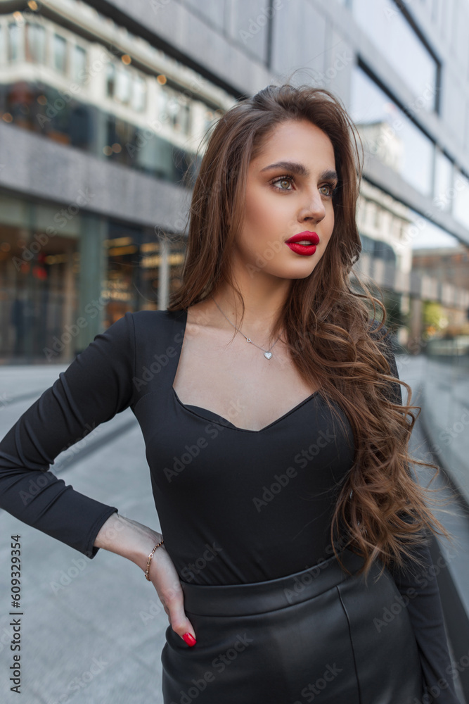 Pretty chic lady with red lips in black fashion elegant clothes walks in the city