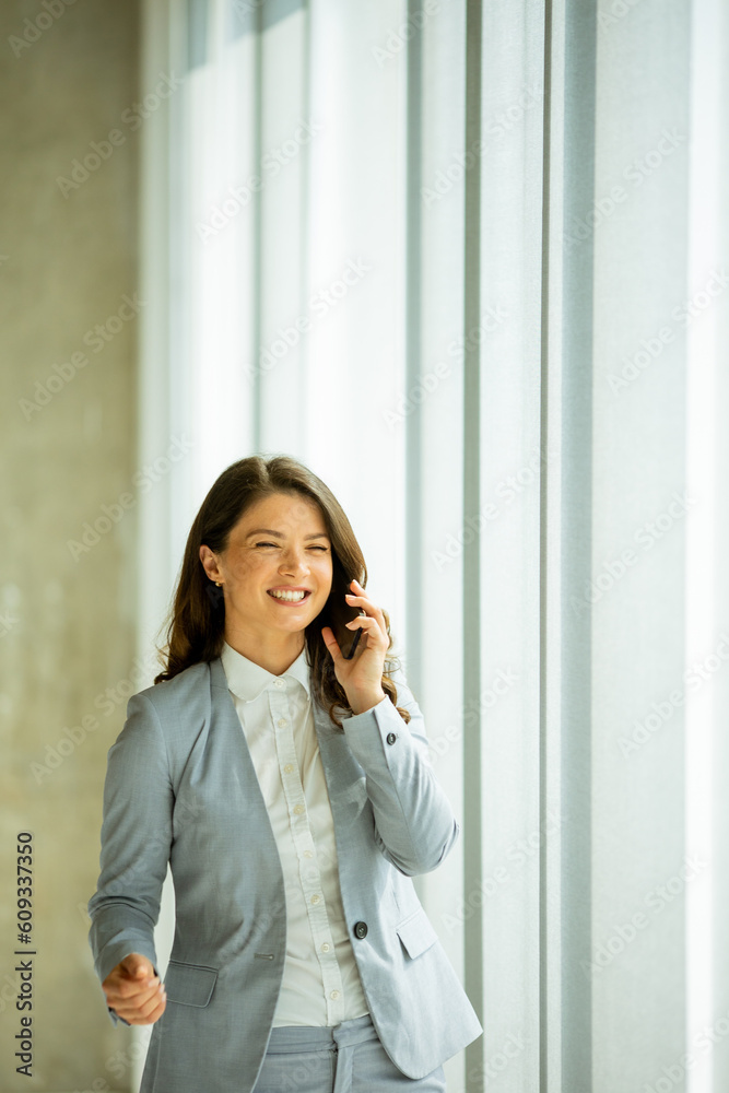 Young woman using mobile phone by the office window Young woman using mobile phone by the office window