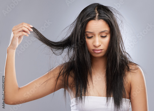 Hair care, damage and face of woman in studio with worry for split end, haircare crisis and weak strand. Beauty, hairdresser and upset female person with frizz, dry or loss problem on gray background photo