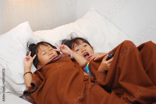 two beautiful Asian girls watching TV in the room while scared