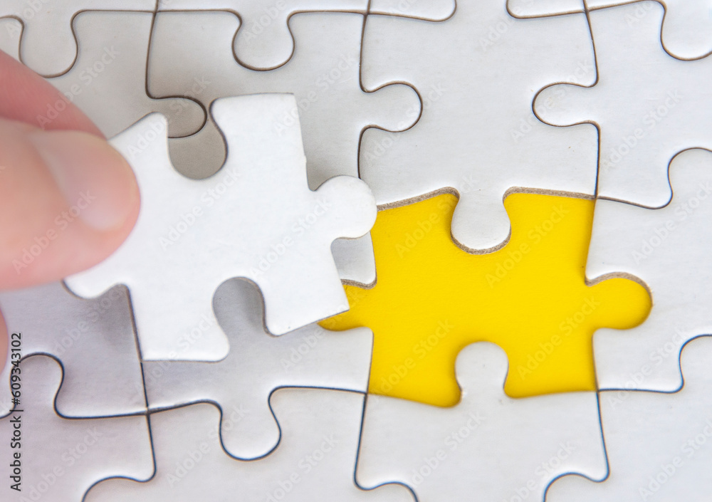 Hand holding separated jigsaw puzzle with customizable space for text. Copy space with yellow background Hand holding separated jigsaw puzzle with customizable space for text. Copy space with yellow background
