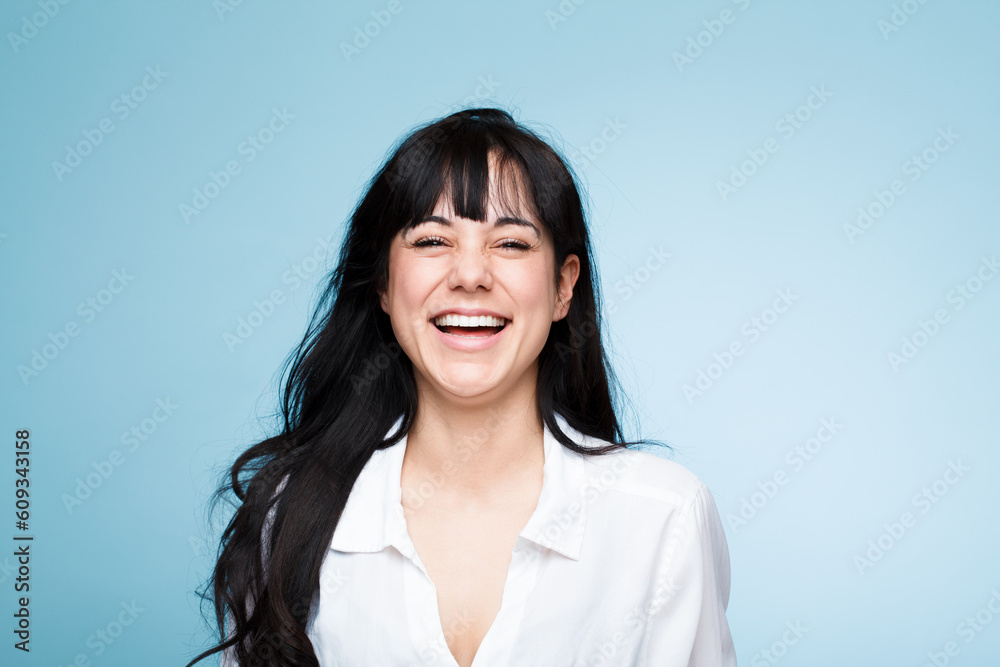Smile, laughing and portrait of a beautiful woman isolated on a blue background in a studio. Happy, young and a headshot of a girl in a shirt with confidence, empowerment and looking stylish Smile, laughing and portrait of a beautiful woman isolated on a blue background in a studio. Happy, young and a headshot of a girl in a shirt with confidence, empowerment and looking stylish