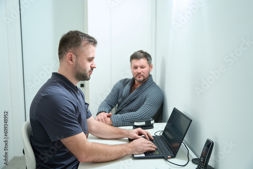 Male nutritionist is typing on a laptop at the workplace