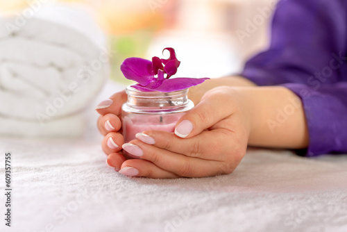 Beautiful women's hands holding a candle with an archidea. Beautiful manicure. Beauty sphere photo