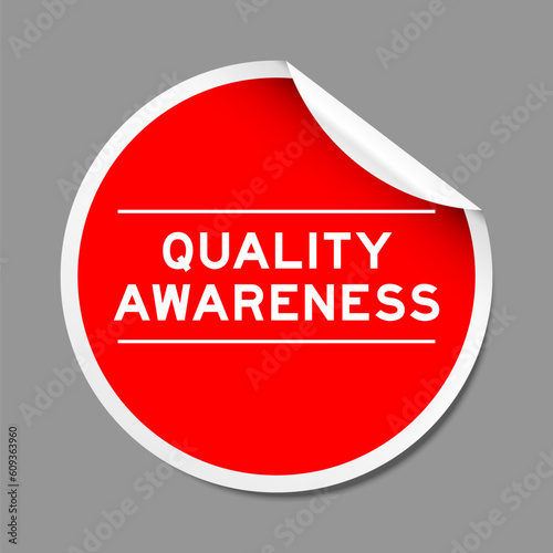 Red color peel sticker label with word quality awareness on gray background