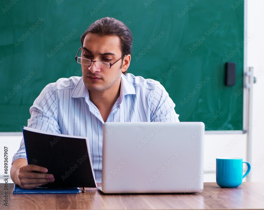 Young male teacher in front of blackboard Young male teacher in front of blackboard