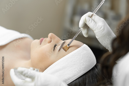 The photo reveals the magic of cosmetic peeling, where each stage of the procedure helps the skin young woman's face to recover and renew. A beautiful patient in a beauty clinic is relaxed and resting