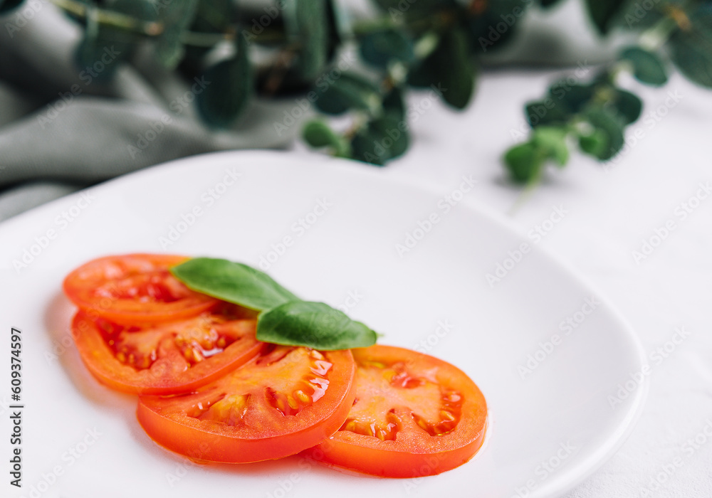 Sliced red tomatoes and basil leaves