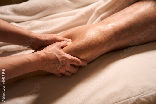 Acupressure practitioner pressing on acupoint on customer calf using thumbs