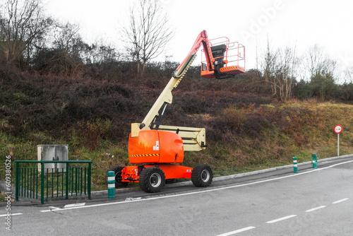 orange and light yellow mobile telescopic crane in the middle of the forest on a winter day, Crane to do power line checking operations