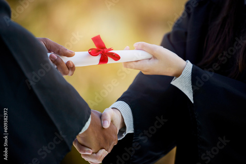 Handshake, graduation diploma and people in success, achievement and congratulations or thank you. Graduate, student or person shaking hands for certificate, excellence and giving award at University