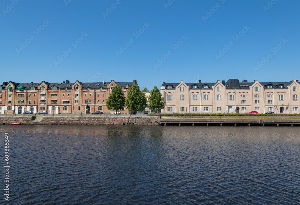 View of buildings by river against clear blue sky