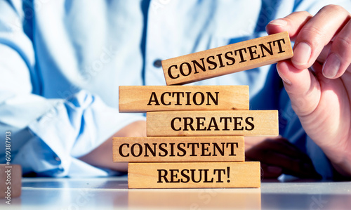 Billede på lærred Close up on businessman holding a wooden block with a Consistent action creates