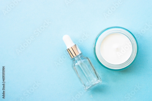 Cream and serum bottle on blue background. Top view with copy space.