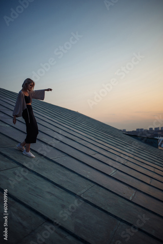 Photo shoot on the roof. Young woman posing in the roof at sunset. People, lifestyle, relaxation concept.