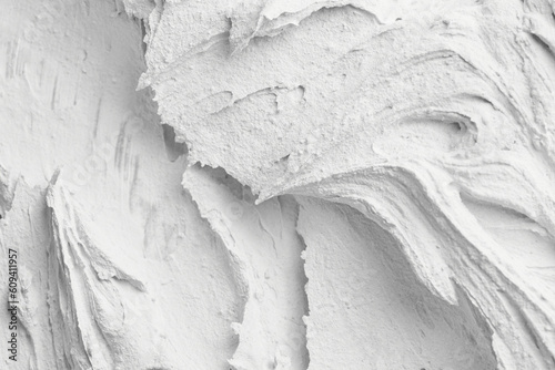 Decorative white putty background. Wall texture with filler paste applied with spatula, chaotic dashes and strokes over plaster. photo