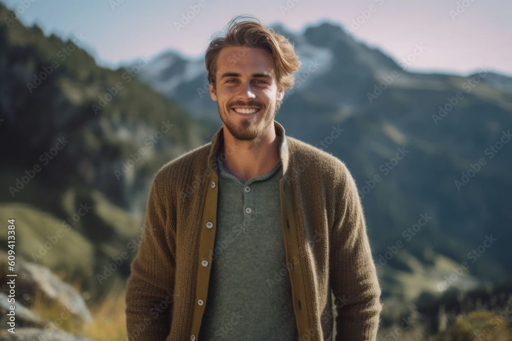 Portrait of a handsome young man smiling at the camera while standing in the mountains Portrait of a handsome young man smiling at the camera while standing in the mountains