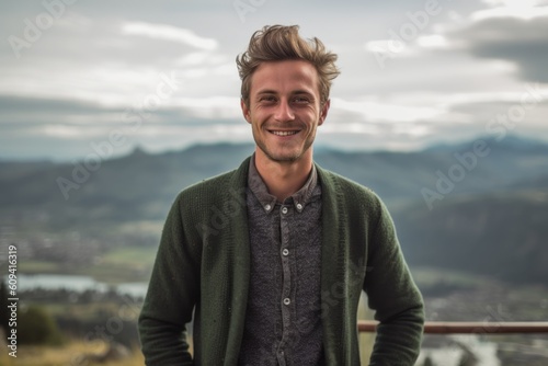 Portrait of a handsome young man standing at the top of a mountain