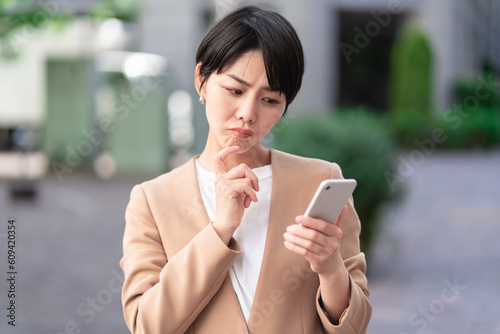 Schilderij op canvas 悩みながらスマートフォンを操作する女性