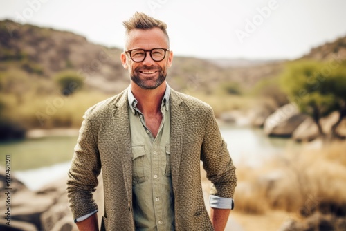Portrait of a handsome hipster man smiling at camera while standing outdoors