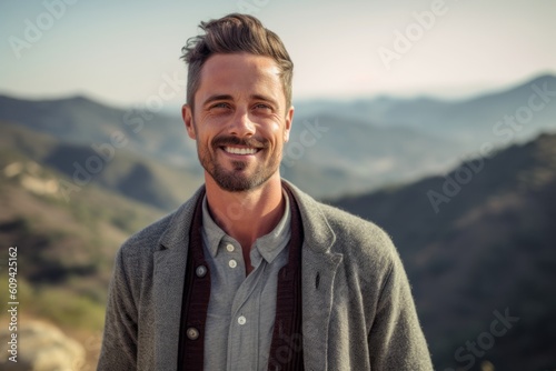 Portrait of handsome man standing on top of mountain in the countryside