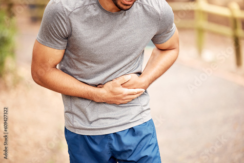 Fitness, stomach ache and man outdoor after running, workout or exercise. Sports, abdominal pain and male athlete in nature with injury, emergency or problem, sick or hernia after training mockup. photo