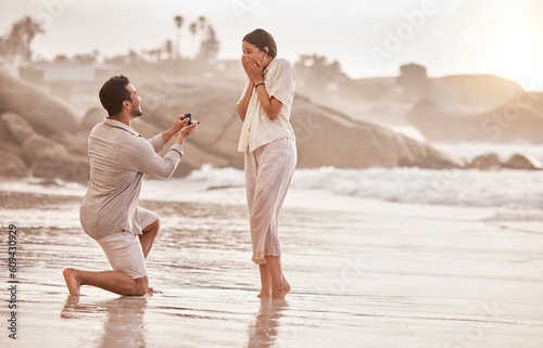 Couple at beach, surprise proposal and engagement with love and commitment with ocean and people outdoor. Travel, seaside and man propose marriage to woman, wow reaction and happiness with care