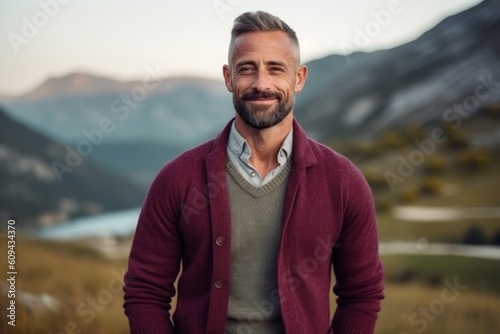 Portrait of a handsome mature man standing in the mountains and looking at camera