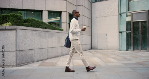 Coffee, walking and a black man in the city in the morning for a commute to work. Side, professional and an African employee on a walk on the sidewalk in a town for a job or career with a drink