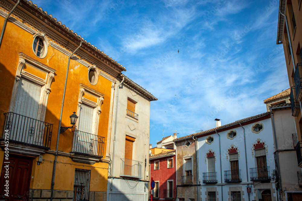 Typical colorful facades of houses in the historic center of Caravaca de la Cruz, in Murcia, Spain, with swallows flying in the blue sky