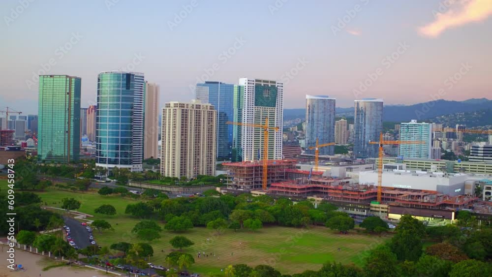Aerial Shot Of Modern Skyscrapers Near People On Beach, Drone Flying Backward Over Sea At Sunset - Oahu, Hawaii Aerial Shot Of Modern Skyscrapers Near People On Beach, Drone Flying Backward Over Sea At Sunset - Oahu, Hawaii