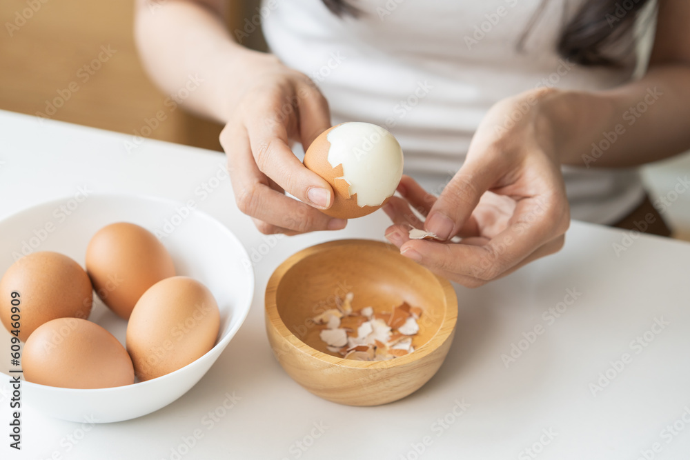 Φωτογραφία Protein in food, keto diet asian young woman hand peeling, shelling chicken boiled egg, prepares ingredient for breakfast meal on table at home