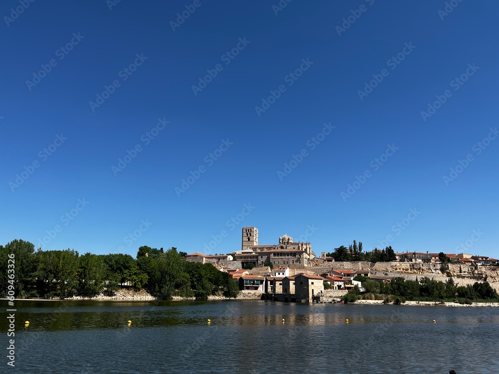 Río sereno y catedral romana bajo un radiante cielo soleado