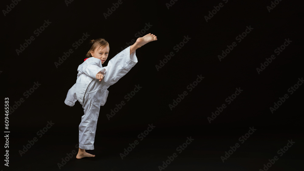 Banner: Asian-Australian girl poses in martial arts Practice taekwondo, karate, judo against a dark background in the studio. Asian kids karate or Taekwondo martial arts. Sport kid training action.