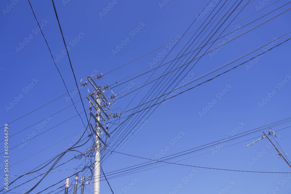 Photo of Power lines, transformers, and electricity poles from below against a blue sky background during the day. Concept for development, industry, energy, urban. Photo of Power lines, transformers, and electricity poles from below against a blue sky background during the day. Concept for development, industry, energy, urban.