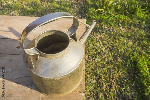 Teko, Ceret, Aluminium Kettle is traditional cooking utensil used to boil water or serving hot drinks such as Tea or coffee. Metal Alumunium Kettle Water Jug. Outdoor sunlight with grass background.