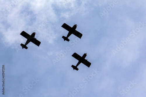 Silhouette of three single engine planes flying lined up in the sky. Sports and leisure. Transportation.
