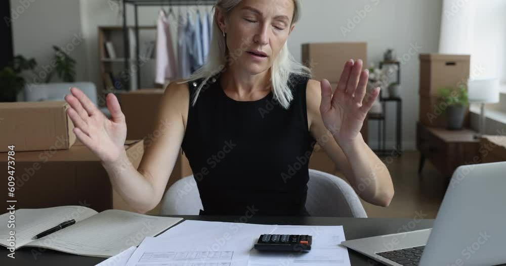 Middle aged entrepreneur woman calculating too high fees, expenses, taxes at workplace, counting small budget in storage, warehouse, finding bad problem, lack of money, failure, bankruptcy risk