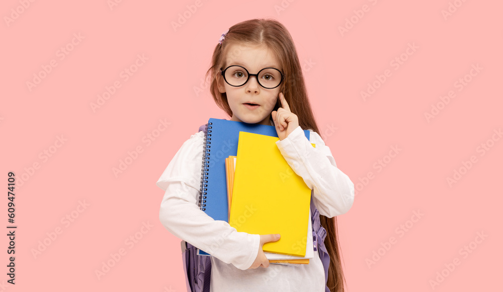 Portrait of a schoolgirl with textbooks and a backpack on a pink background. Back to school
