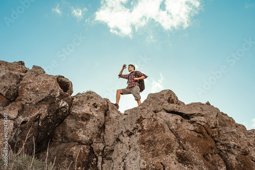 Man getting ready to climb up mountain looking up at the challenge before him. Believe in yourself, overcoming challenges, pushing forward concept.