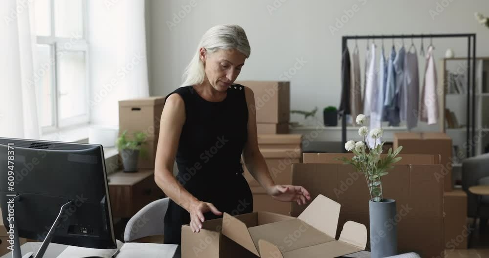 Serious mature Internet store manager packing box for shipping, wrapping product at workplace table, preparing small logistic container in home office warehouse Serious mature Internet store manager packing box for shipping, wrapping product at workplace table, preparing small logistic container in home office warehouse