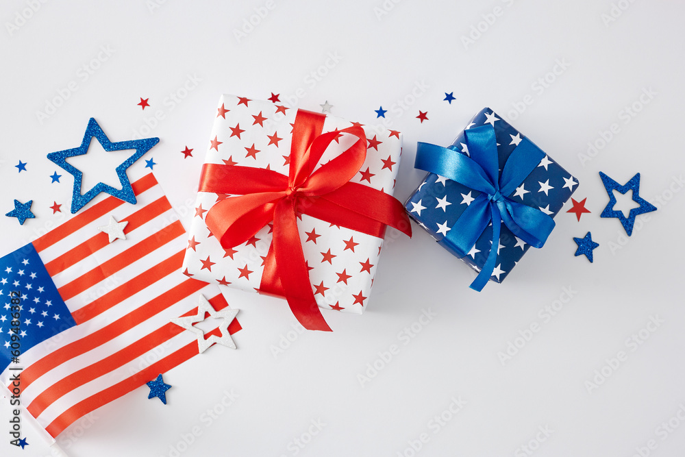 4th of July gift theme concept. Top view flat lay of gift boxes in patriotic colors, american flag, red, blue, white glittering stars on white background 4th of July gift theme concept. Top view flat lay of gift boxes in patriotic colors, american flag, red, blue, white glittering stars on white background