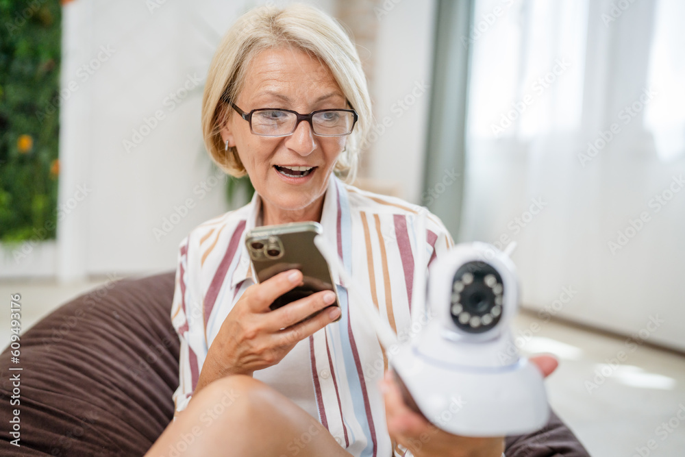 woman mature caucasian hold adjust home security camera and smartphone woman mature caucasian hold adjust home security camera and smartphone