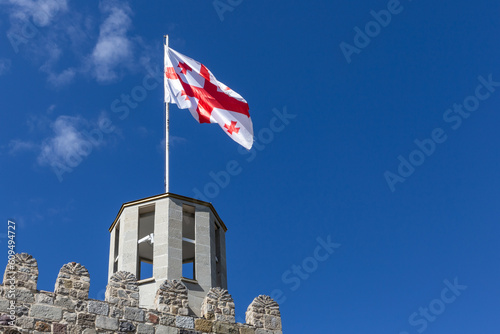 Quadro su tela Georgian national flag (five-cross flag) waving on the wind against clear blue sky at the top of ancient watchtower of Akhaltsikhe (Rabati) Castle, Georgia