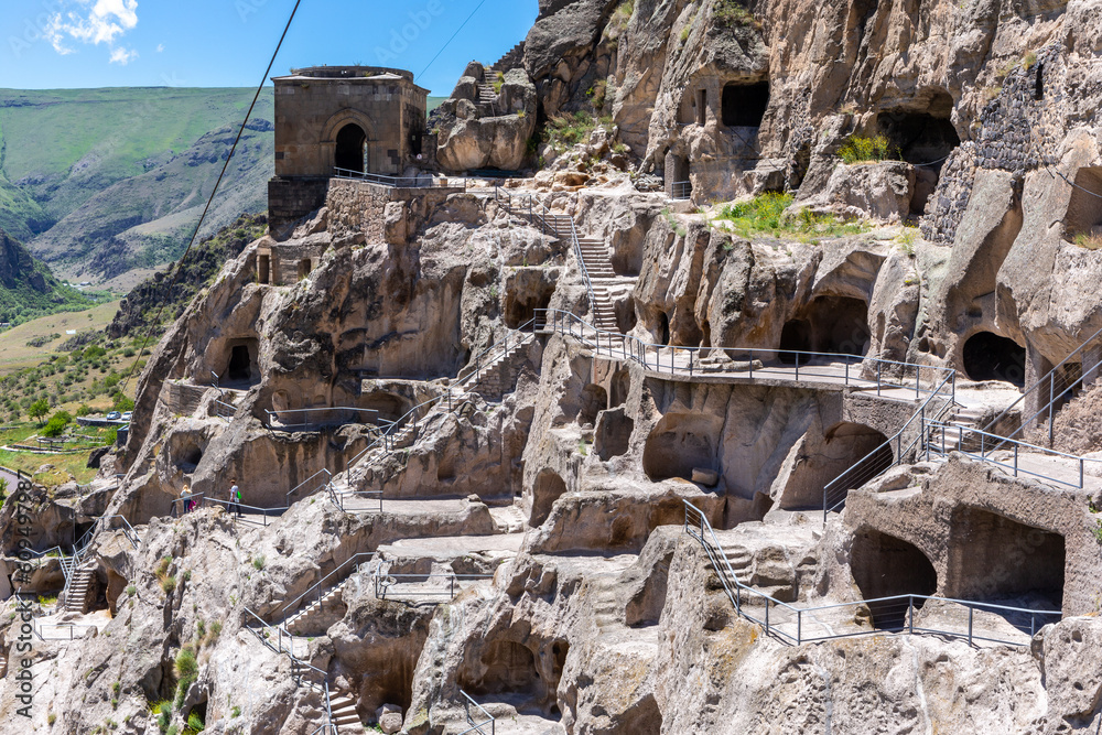 Vardzia cave monastery complex in Georgia, mountain slope with caves, tunnels and dwellings carved in the rock, bell tower building in the background. - obrazy, fototapety, plakaty 