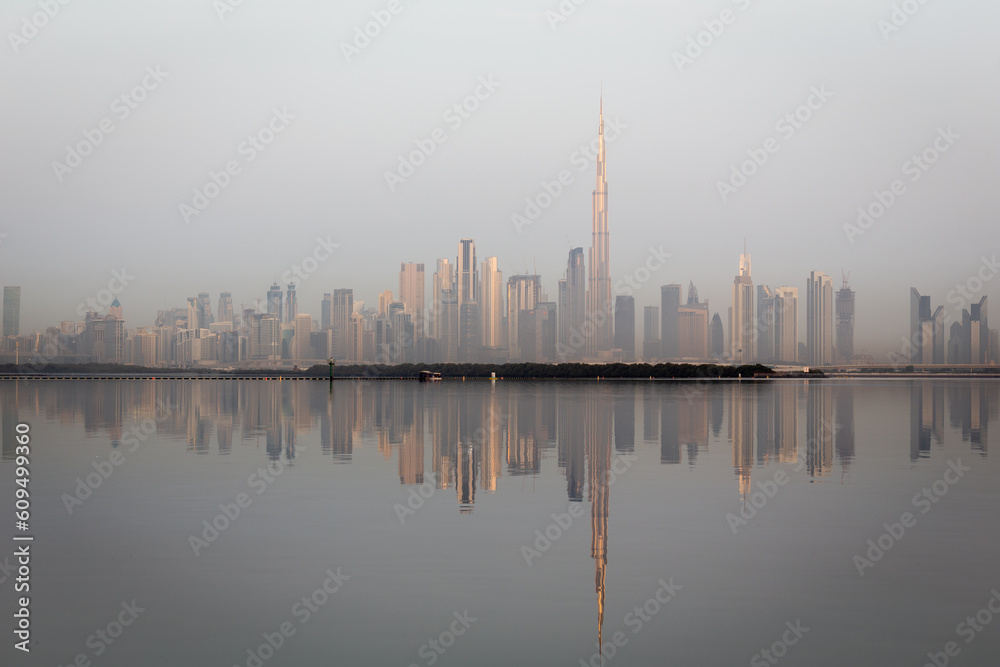 Dubai Downtown skyline landscape with the skyscrapers reflecting golden sun and reflections in Dubai Creek, sunrise.