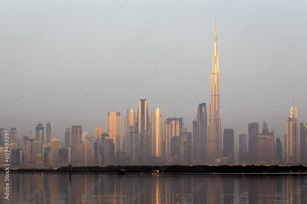 Dubai Downtown skyline landscape with the skyscrapers reflecting golden sun and reflections in Dubai Creek, sunrise.