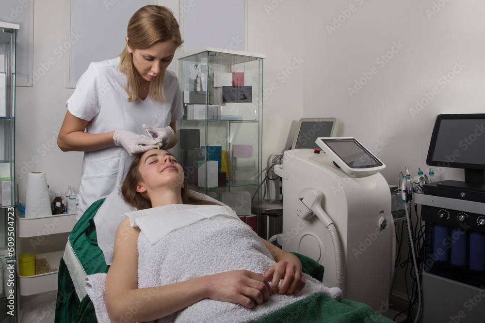 Doctor female giving Botox injection in forehead Doctor female giving Botox injection in forehead