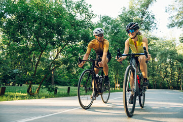 Couple riding bicycles outside of the city and wearing helmets and sunglasses